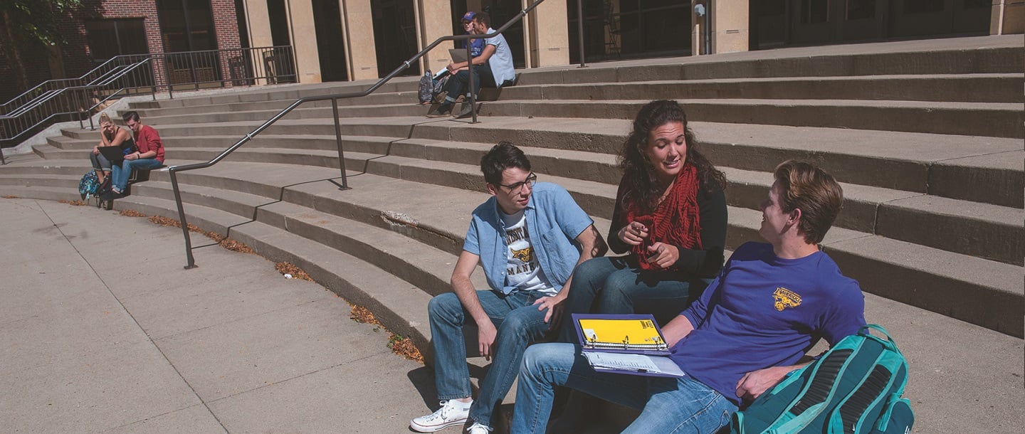 Students sitting on the stairs outside of the Theatre Arts building
